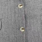 Close-up of a tailored suit fabric with a classic herringbone pattern and two cream-colored buttons.