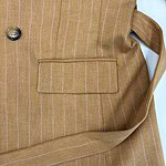 Close-up of a men's brown pinstripe blazer with a pocket and button detail, suitable for formal or business wear.