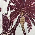 Close-up of a men's shirt with a tropical leaf pattern in shades of burgundy and cream, featuring white buttons.