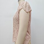 Close-up of a pink lace women's top displayed on a mannequin, showcasing intricate lace patterns and delicate craftsmanship.