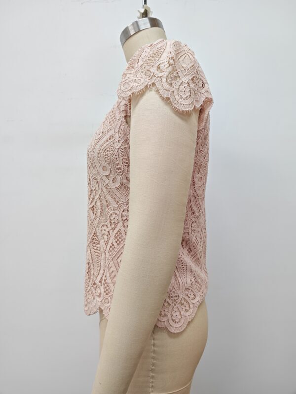 Close-up of a pink lace women's top displayed on a mannequin, showcasing intricate lace patterns and delicate craftsmanship.