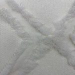 Close-up of white fabric featuring textured surface and frayed edges, ideal for fashion or textile design.