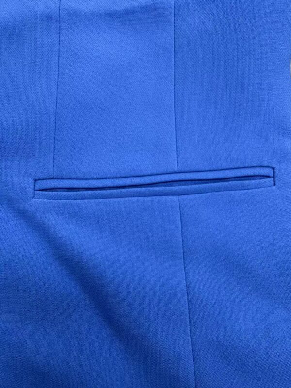 Close-up of a blue suit jacket with a neatly stitched horizontal pocket, showcasing fine tailoring and fabric quality.