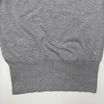 Close-up of a gray knitted sweater with a small embroidered logo on the lower right side, suitable for casual fashion.