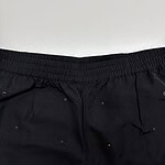 Close-up of black shorts featuring eyelet embellishments and elastic waistband, perfect for casual or athletic wear.