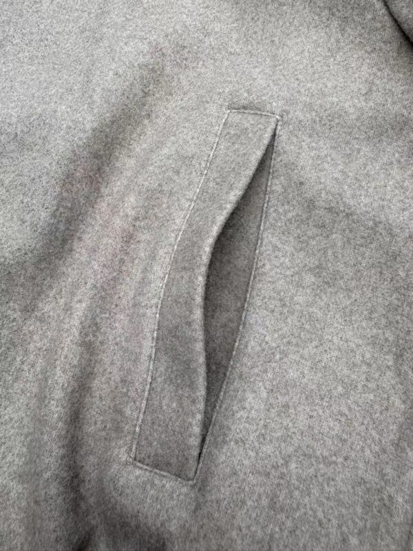Close-up of a gray wool coat pocket with a sleek, minimalist design, showcasing fine stitching and fabric texture.