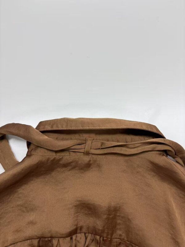 Close-up of a brown leather bag with a strap, showcasing its texture and design, suitable for fashion and accessory SEO.