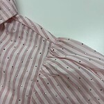 Close-up of a pink and white striped dress with silver embellishments, showcasing fabric details and design elements.