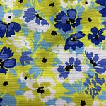 Colorful floral fabric with blue, white, and yellow flowers and green leaves, suitable for fashion and home decor.