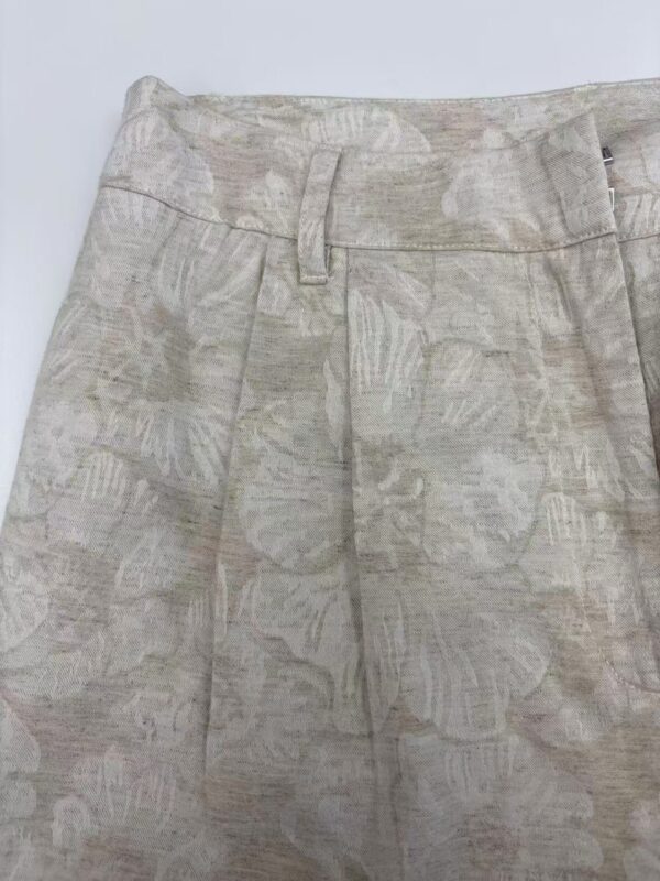 Close-up of beige floral-patterned women's trousers with belt loops and tailored fit, perfect for casual or semi-formal occasions.