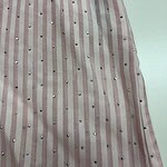 Close-up of pink and white striped fabric with small metallic embellishments, suitable for fashion or dress design.