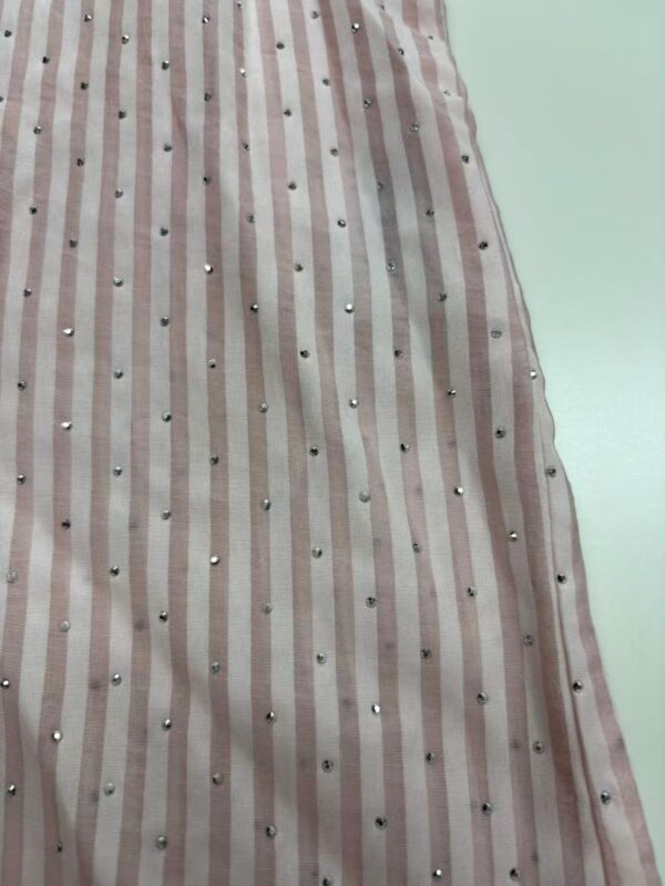 Close-up of pink and white striped fabric with small metallic embellishments, suitable for fashion or dress design.