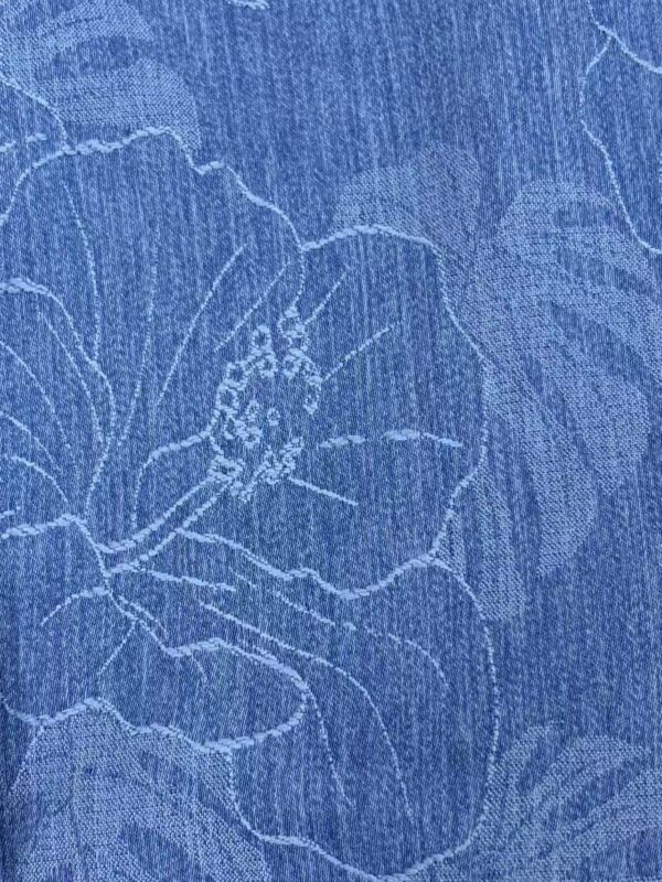 Close-up of blue fabric with delicate floral embroidery, showcasing intricate stitching and elegant design suitable for fashion and home decor.