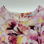Close-up of a women's dress with a vibrant floral print in pink, yellow, and purple shades, made from lightweight fabric, perfect for spring and summer wear.