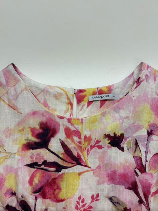 Close-up of a women's dress with a vibrant floral print in pink, yellow, and purple shades, made from lightweight fabric, perfect for spring and summer wear.