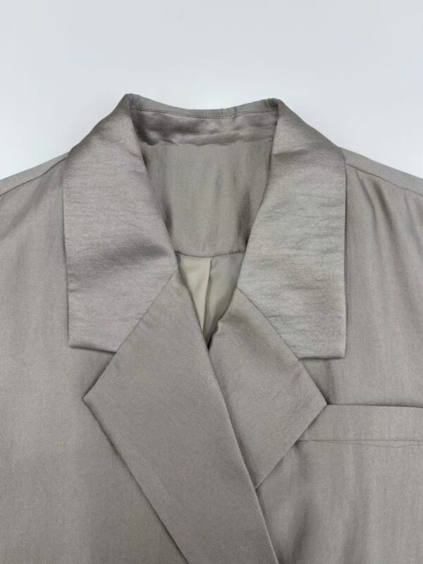 Close-up of a stylish satin blazer with a notched lapel, perfect for formal or evening wear, showcasing smooth fabric and tailored design.