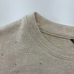 Close-up of a beige sweater adorned with small rhinestones around the neckline, showcasing elegant casual fashion for women.