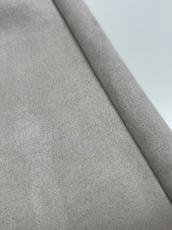 Close-up of light gray wool fabric showcasing its soft texture and fine weave, ideal for high-quality fashion and upholstery.