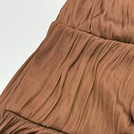 Close-up of a brown pleated dress showcasing detailed fabric texture and stylish design, perfect for fashion-forward women.