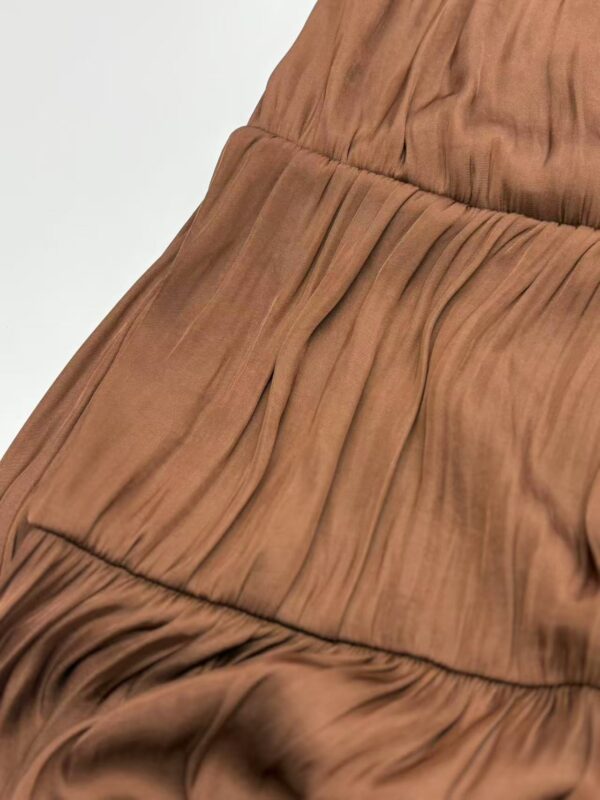 Close-up of a brown pleated dress showcasing detailed fabric texture and stylish design, perfect for fashion-forward women.