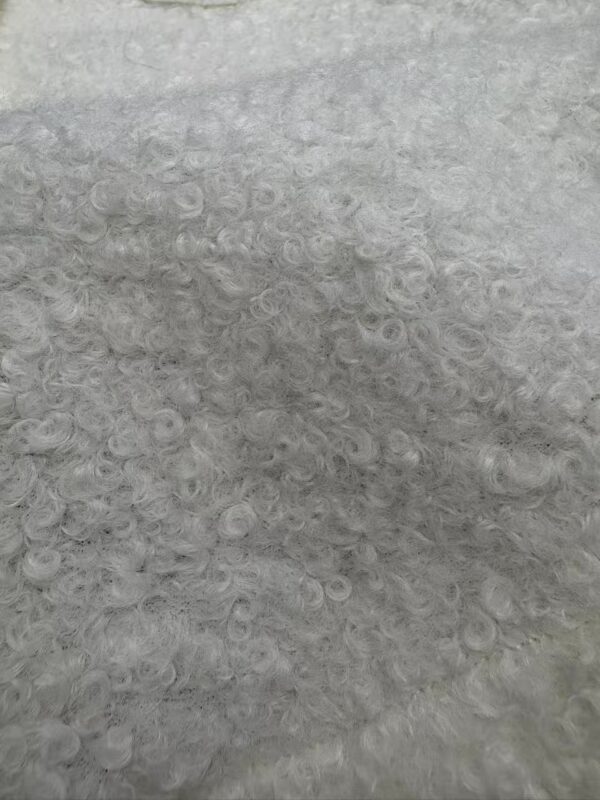 Detailed close-up of curly gray hair showing fine, soft, and dense curls with a natural shine, ideal for hair care and styling content.