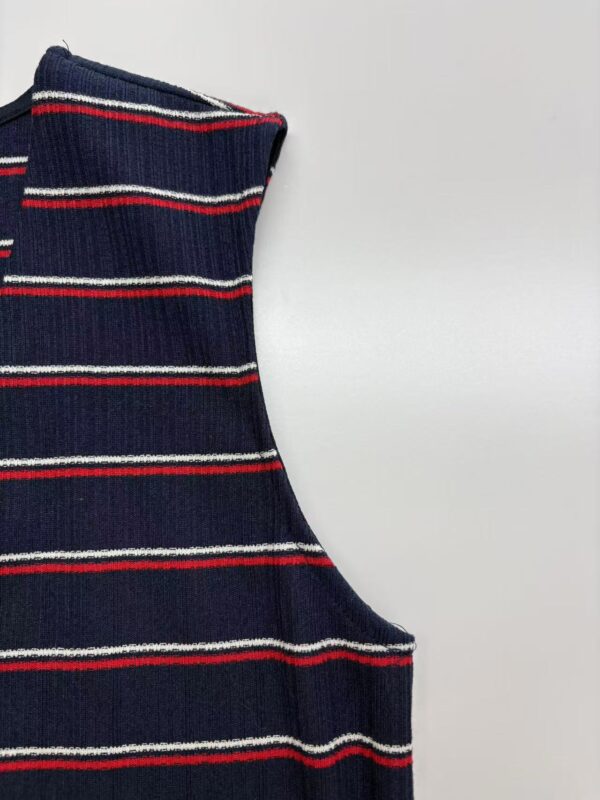 Close-up of a navy blue knit sweater with red, white, and blue horizontal stripes, showcasing a casual and stylish design.
