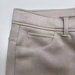 Close-up of beige women's trousers showing waistband, belt loop, and front pocket details.