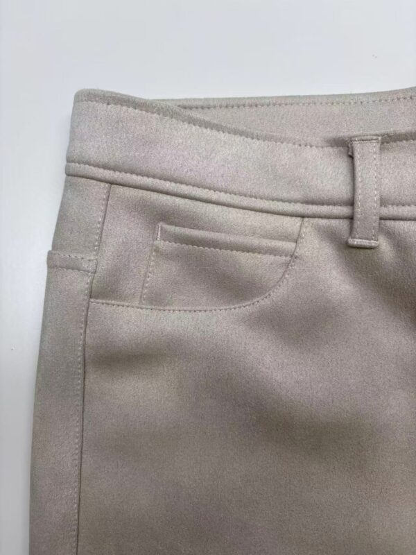 Close-up of beige women's trousers showing waistband, belt loop, and front pocket details.