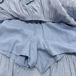 Close-up of a light blue dress featuring ruffled details and lace trim, perfect for stylish occasions.