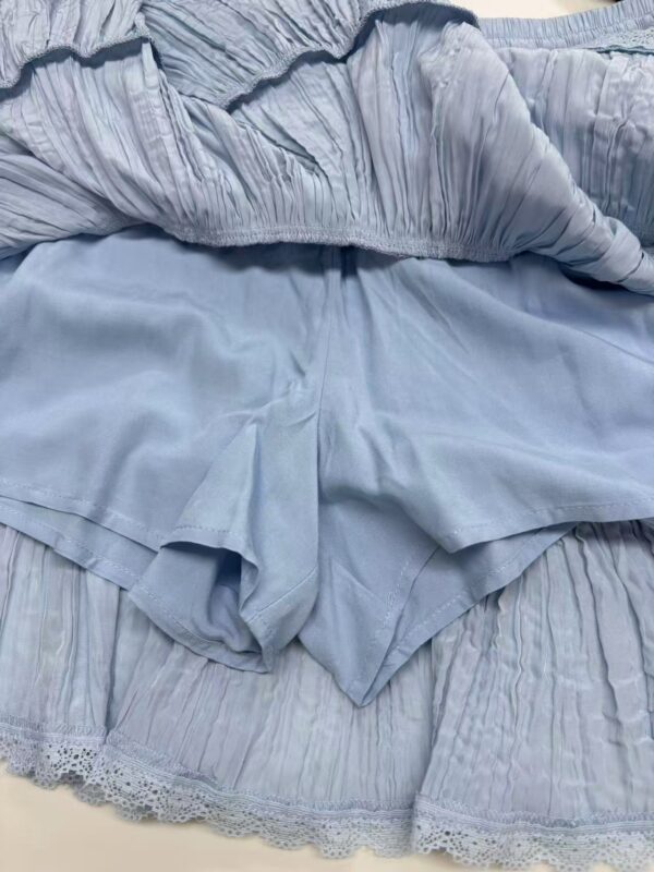 Close-up of a light blue dress featuring ruffled details and lace trim, perfect for stylish occasions.