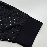 Close-up of a black dress sleeve with sequins and a black cuff, showcasing stylish evening wear suitable for formal occasions.