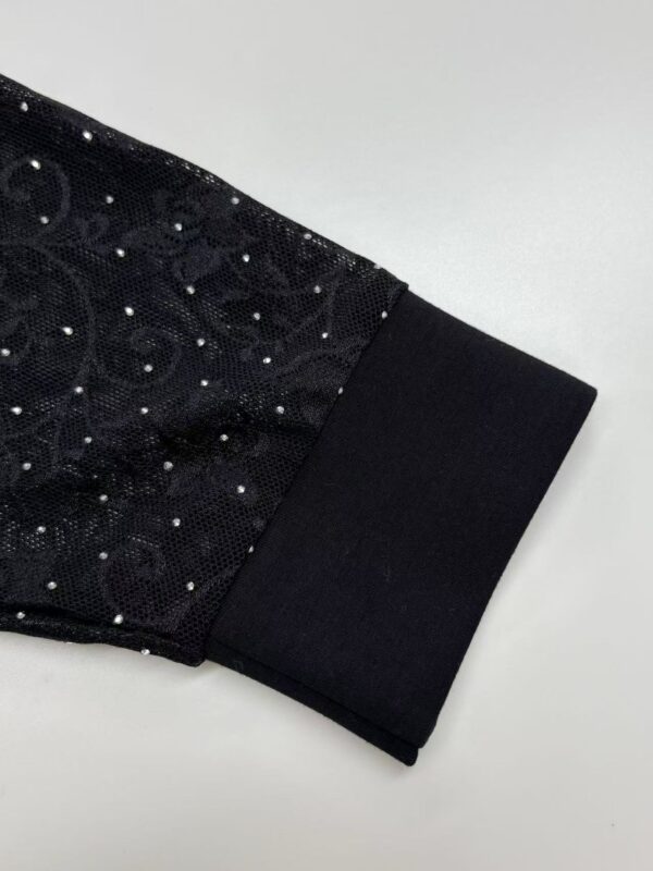 Close-up of a black dress sleeve with sequins and a black cuff, showcasing stylish evening wear suitable for formal occasions.