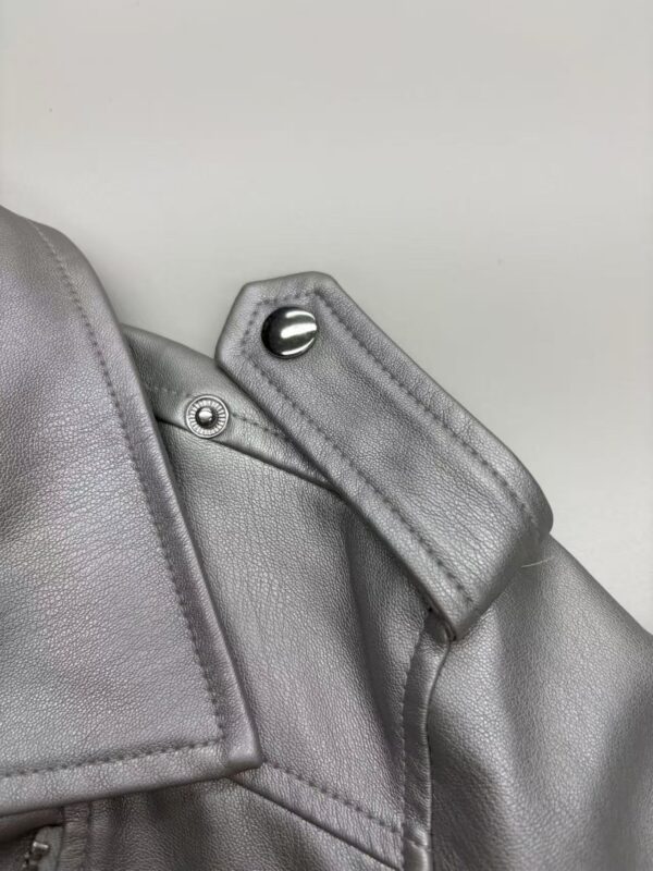 Detailed close-up of a gray leather jacket shoulder with button and stitching, showcasing high-quality craftsmanship and stylish design.
