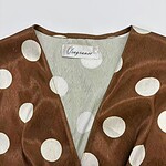 Elegant brown satin dress with large white polka dots, V-neckline, and soft fabric, perfect for stylish occasions and fashion-forward outfits.