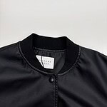 Close-up of a black leather bomber jacket with snap buttons and ribbed collar, perfect for fashion-forward casual wear.