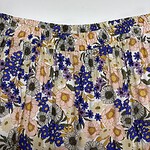 Close-up of a floral patterned skirt with pink, blue, and black flowers on a light background, featuring an elastic waistband.