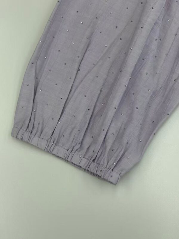 Close-up of grey fabric with small embellishments, showcasing fine texture and detailed craftsmanship, ideal for fashion or textile design.
