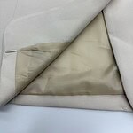 Close-up of a light beige suit jacket with a single button and inner lining visible, showcasing high-quality tailoring and fabric.