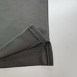 Detailed view of the stitched edge of a grey fabric material, showing clean stitching and smooth texture, suitable for clothing or upholstery.