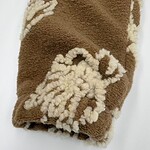 Close-up of a brown sherpa fleece blanket featuring a white sheep design, soft texture, ideal for cozy home decor and winter warmth.