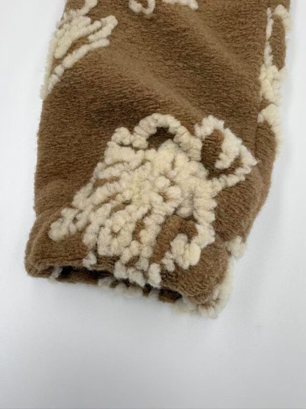 Close-up of a brown sherpa fleece blanket featuring a white sheep design, soft texture, ideal for cozy home decor and winter warmth.