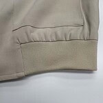 Close-up of beige sweatshirt cuff showing ribbed elastic band and smooth fabric, highlighting quality and design.