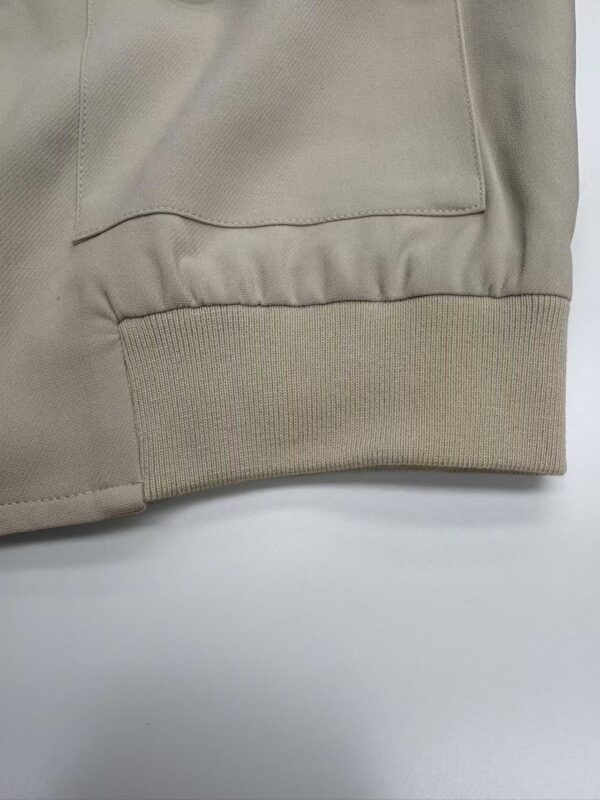 Close-up of beige sweatshirt cuff showing ribbed elastic band and smooth fabric, highlighting quality and design.