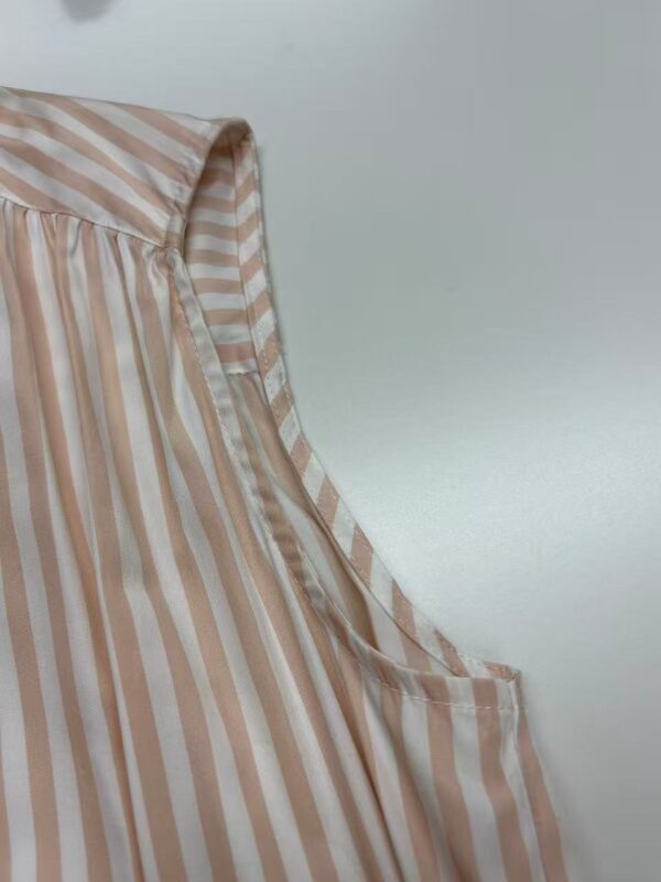 Close-up of a stylish women's blouse with beige and white vertical stripes, featuring a pleated design and a soft, flowing fabric.