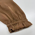 Close-up of a brown fabric sleeve with gathered elastic cuff, showcasing stylish and comfortable design suitable for fashion-forward outfits.