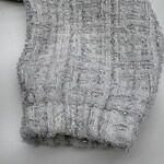 Close-up of silver tweed fabric with textured weave and subtle shimmer, ideal for luxury fashion and high-end clothing design.