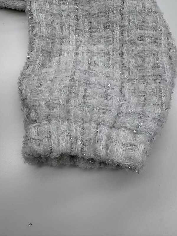 Close-up of silver tweed fabric with textured weave and subtle shimmer, ideal for luxury fashion and high-end clothing design.
