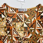 Close-up of a dress with a vibrant geometric pattern in orange, black, white, and yellow colors, featuring intricate triangles and lines.