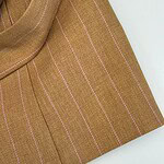 Close-up of a brown pinstripe blazer with pinkish-white vertical stripes, showcasing tailored fabric and design details for fashionable women's wear.