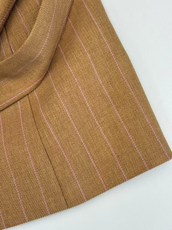Close-up of a brown pinstripe blazer with pinkish-white vertical stripes, showcasing tailored fabric and design details for fashionable women's wear.